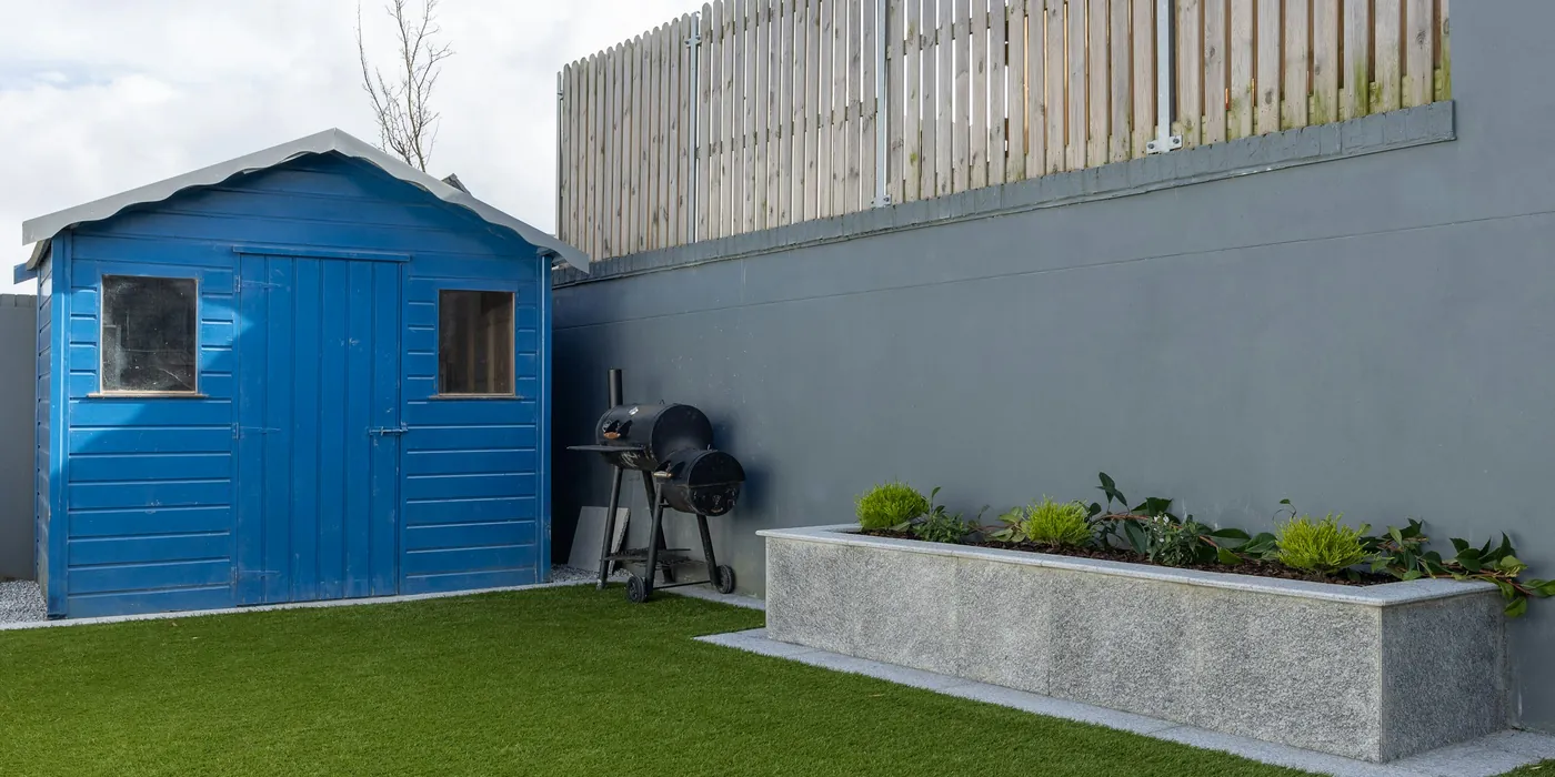 An enclosed back garden laid to artificial grass, with a shed and fencing