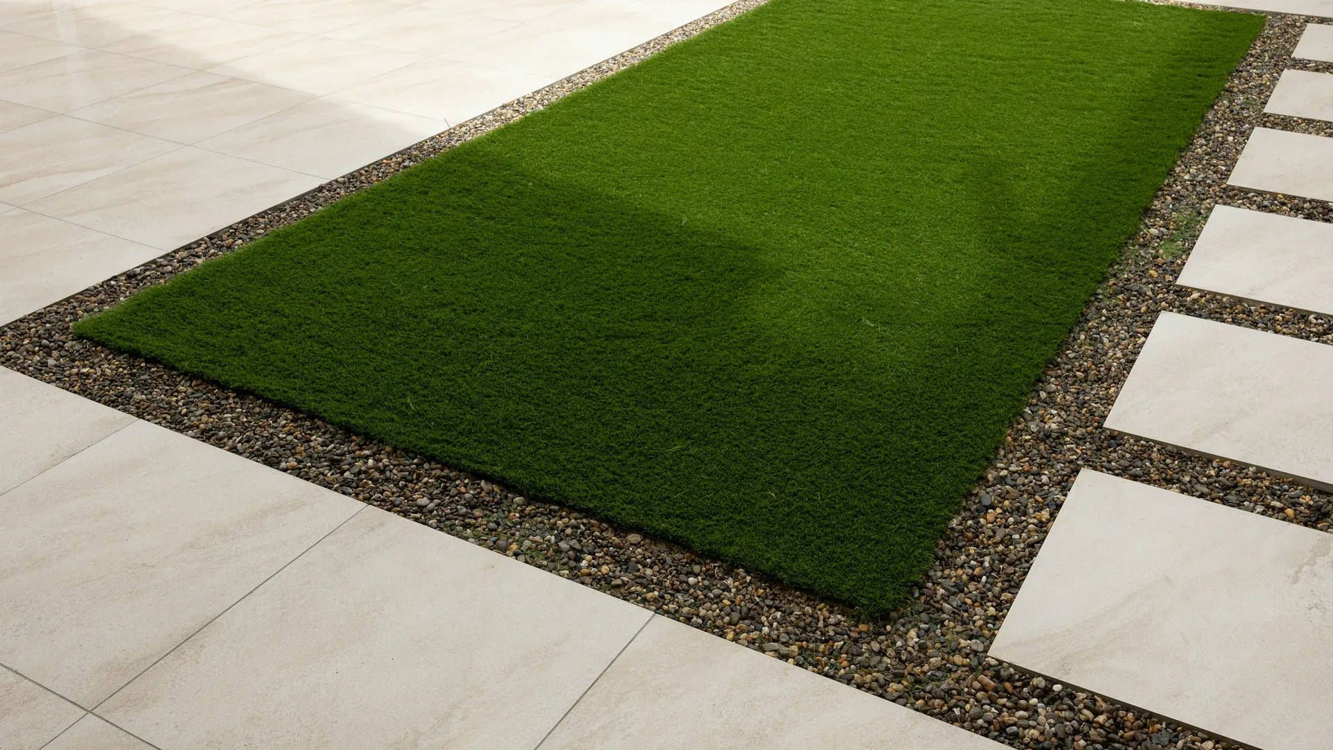 A laid artificial lawn edged with paving slabs and gravel