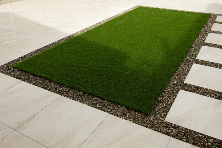 A laid artificial lawn edged with paving slabs and gravel